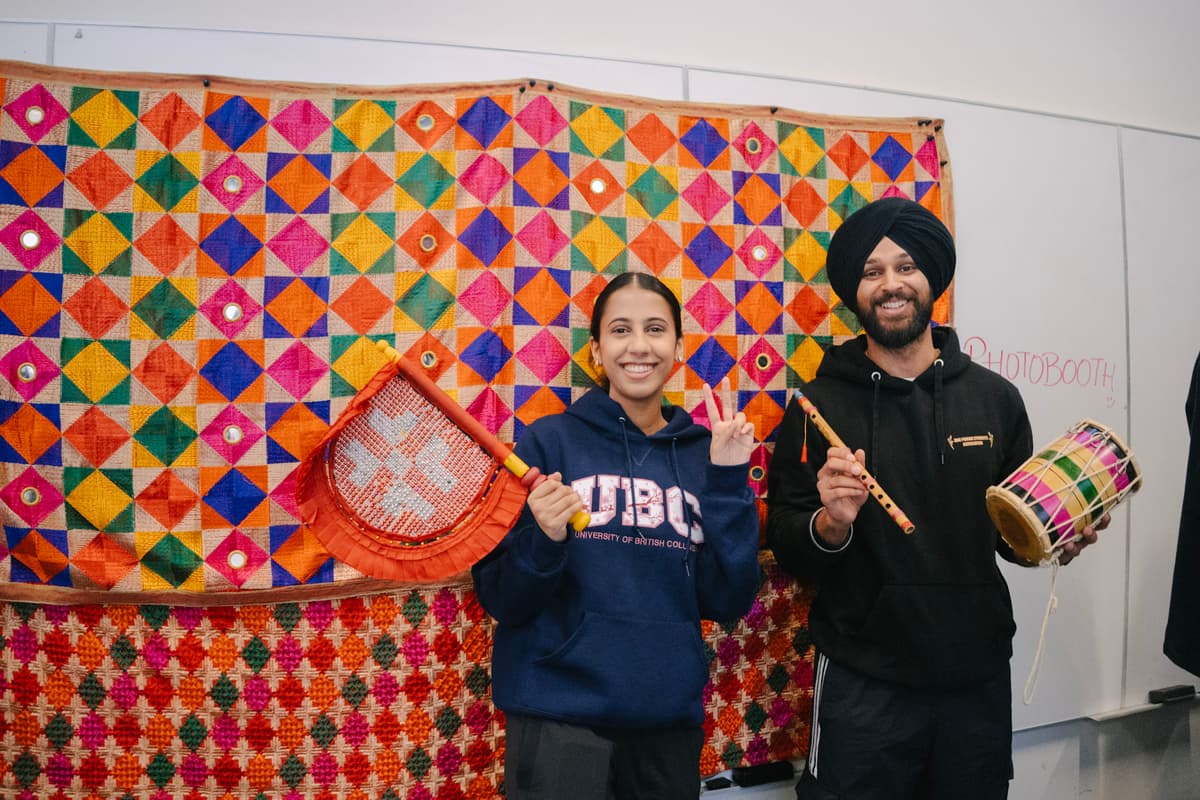 Two people holding traditional Punjabi props